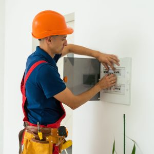 Young adult electrician builder engineer inspecting electric counter equipment in distribution fuse box Young adult electrician builder engineer inspecting electric counter equipment in distribution fuse box.